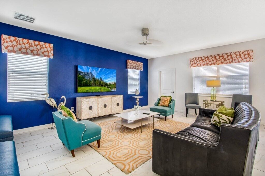 A living room with a blue accent wall, a flat-screen TV, a coffee table, and a sofa.