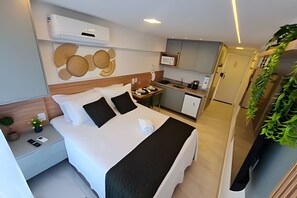 Ein Hotelzimmer mit Bett, Nachttisch und einer kleinen Küchenzeile.
