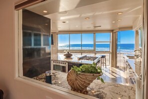 A kitchen with a view of the ocean, a large window, and a marble countertop. - Boardwalk Paradise 2 | New Mid-Stay Home w/ Endless Sunsets (San Diego)