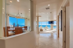 Un interior moderno con comedor, una zona de estar con vistas y un pasillo que conduce a una puerta.