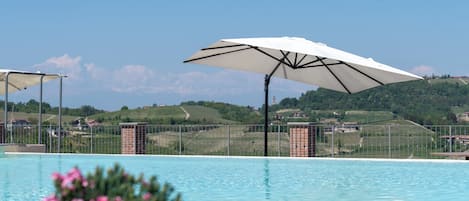 A swimming pool with a view of a hilly landscape and a fence.