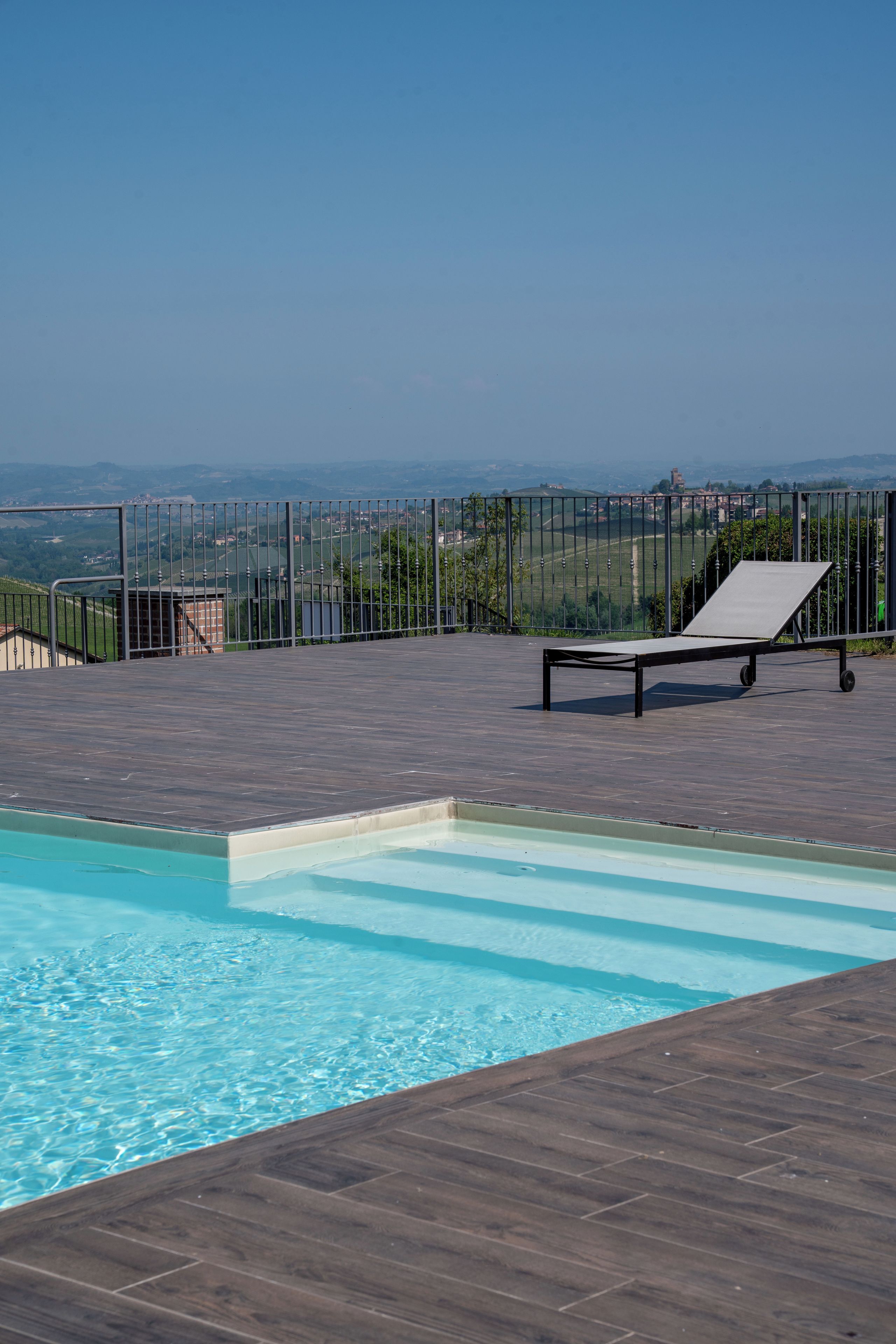 Ein Pool mit Liegestuhl und Blick auf eine entfernte Landschaft.
