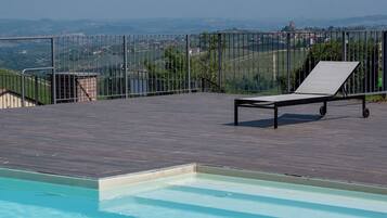 Ein Pool mit Liegestuhl und Blick auf eine entfernte Landschaft.