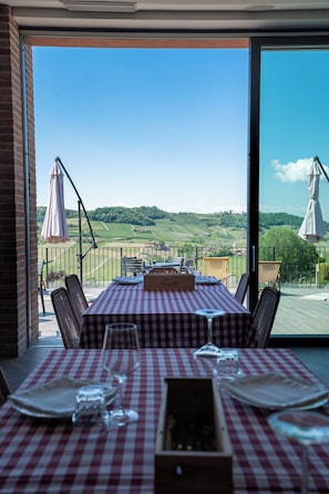 Comedor con una mesa para dos, con vistas a un viñedo.