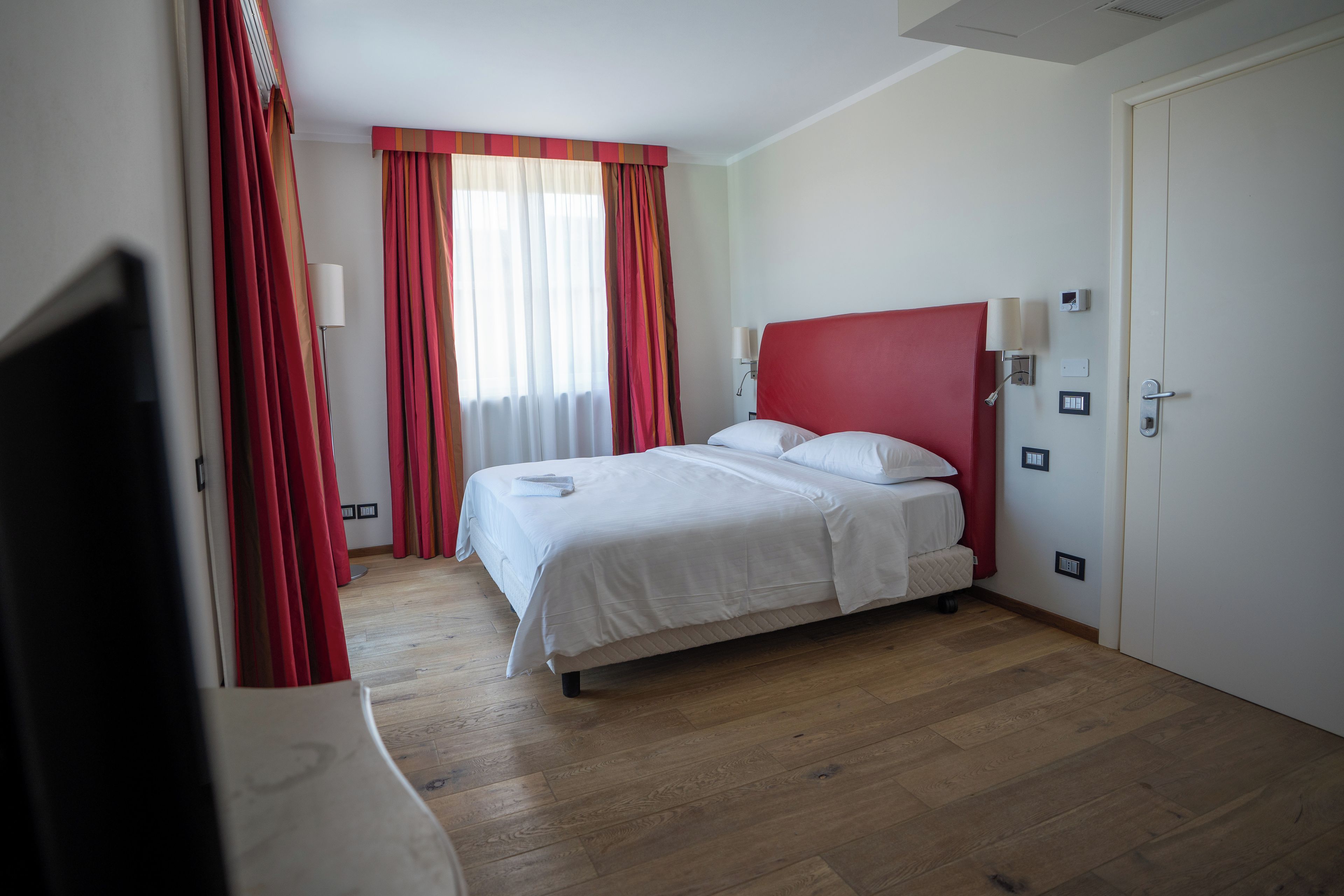 Una habitación de hotel con cama, televisor y puerta.