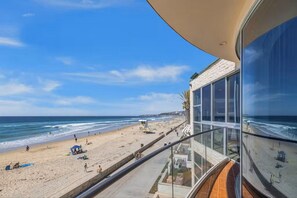Uitzicht op het strand vanaf een balkon, met een heldere lucht.