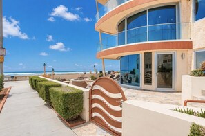 A beachfront hotel with a curved glass facade, outdoor seating, and a clear view of the ocean. - NEW Boardwalk Paradise | Luxury Family Oceanfront Home Mission Beach (San Diego)