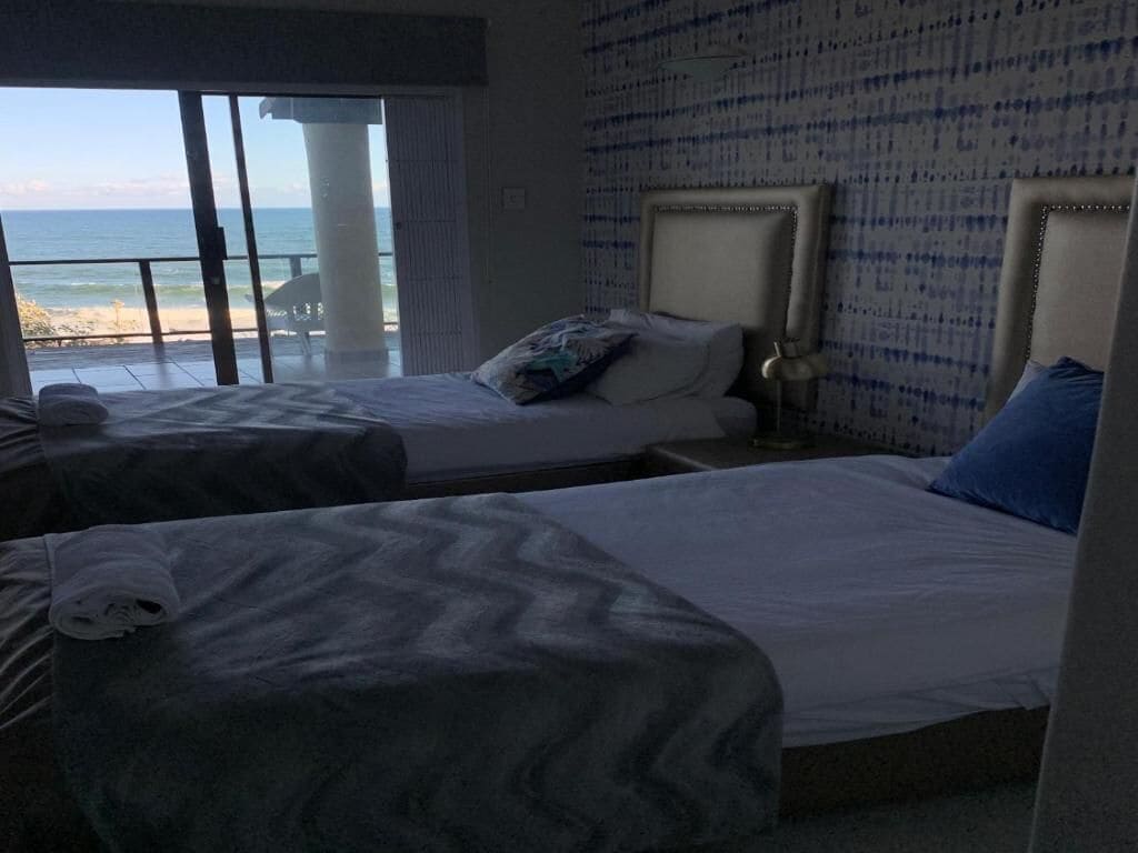Une chambre d’hôtel avec deux lits, une vue sur la plage et une grande fenêtre.