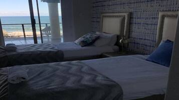 Une chambre d’hôtel avec deux lits, une vue sur la plage et une grande fenêtre.