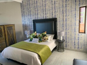 A hotel room with a bed, a nightstand, a lamp, and a patterned wall.