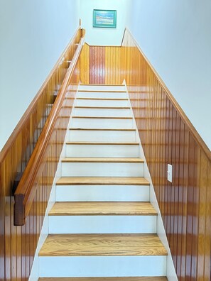 A wooden staircase with white steps leading upwards, flanked by wooden railings.