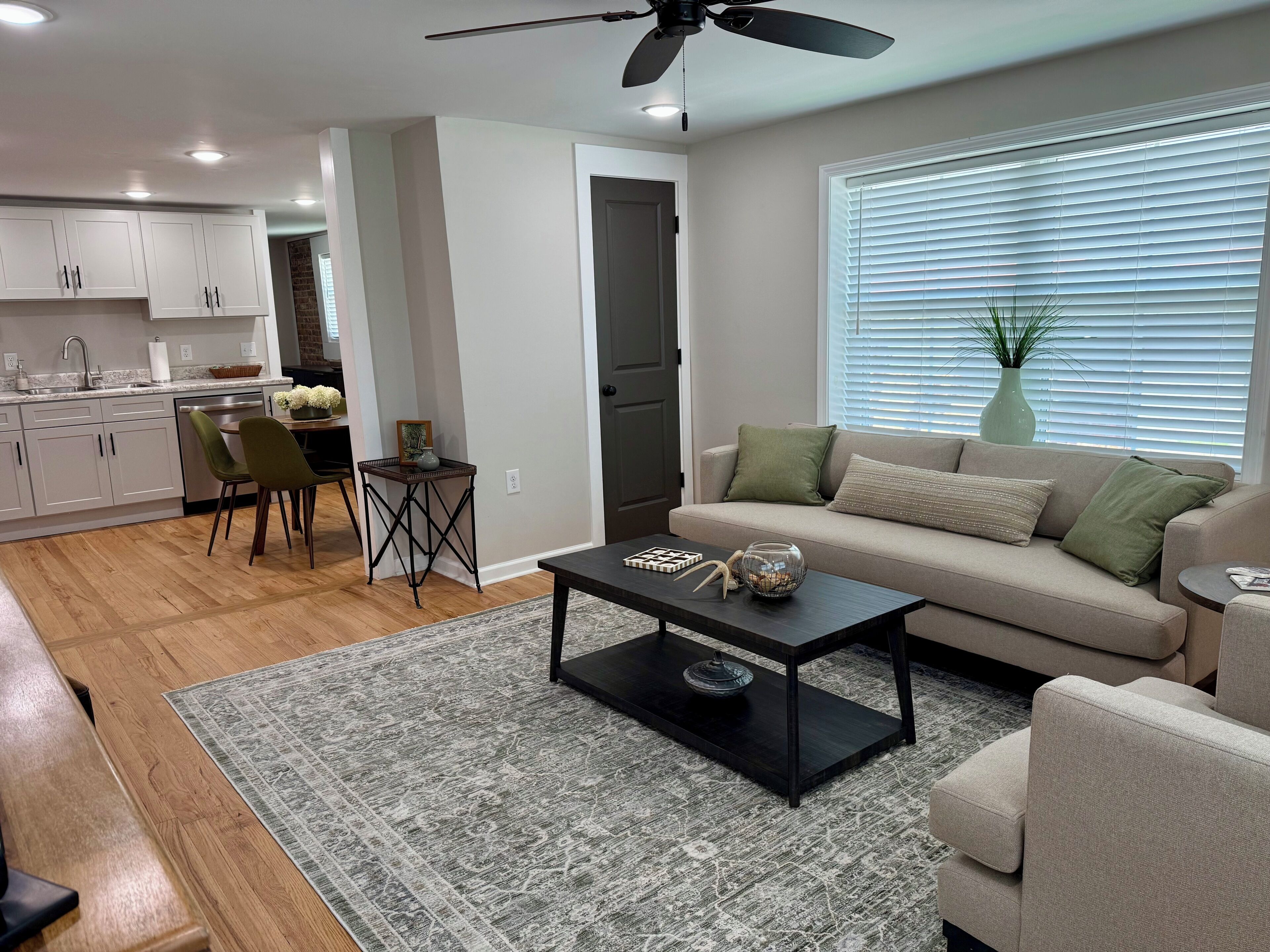 A modern living room with a sofa, coffee table, and a dining area with chairs and a small table.