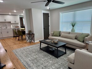 A modern living room with a sofa, coffee table, and a dining area with chairs and a small table. - Newly renovated 1-bedroom apartment in pleasant Gamaliel (Gamaliel)