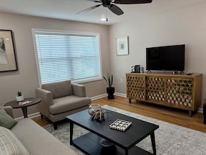 A living room with a sofa, a coffee table, a TV, and a wooden cabinet.