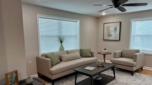 A living room with a sofa, armchairs, a coffee table, and a ceiling fan.