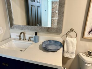 A bathroom with a white sink, a blue soap dispenser, a towel ring, and a toilet. - Newly renovated 1-bedroom apartment in pleasant Gamaliel (Gamaliel)