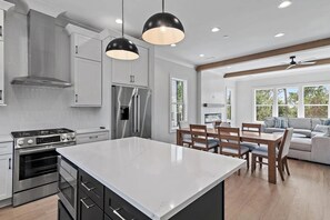 A modern kitchen with a central island, stainless steel appliances, and pendant lighting. - 30A House Co: The Henderson House (SANTA RSA BCH)