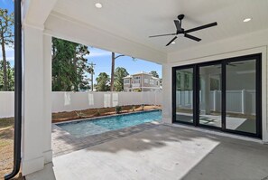 A covered outdoor area with a pool, a ceiling fan, and a view of a residential neighborhood. - 30A House Co: The Henderson House (SANTA RSA BCH)