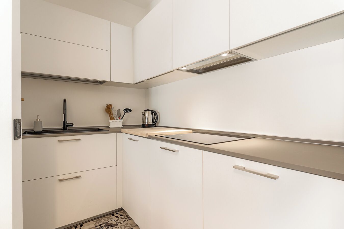 A modern kitchen with white cabinets, a stainless steel sink, and a built-in stove.