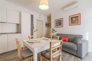 Um espaço de estar moderno com uma mesa de jantar, cadeiras, um sofá cinzento e duas obras de arte emolduradas na parede.