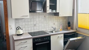 Una cocina moderna con armarios blancos, un microondas negro y un horno empotrado.