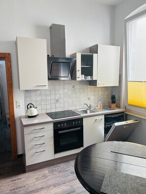 Una cocina moderna con armarios blancos, un microondas negro y un horno empotrado.