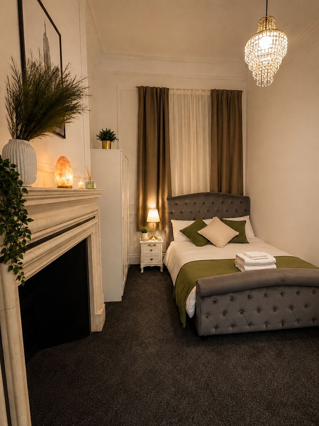 A bedroom with a bed, bedside table, lamp, and a decorative item on the nightstand.