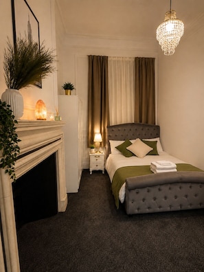 Een slaapkamer met een bed, nachtkastje, lamp en een decoratief object op de nachtkast.