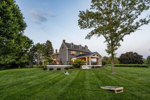 A two-story house with a covered porch, surrounded by a well-maintained lawn and trees.