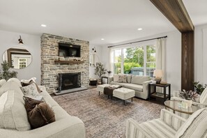 A living room with a stone fireplace, a sofa, a coffee table, and a TV mounted on the wall. - Welcome to the magic of Langford Creek Farm (Chestertown)