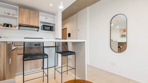 Une cuisine moderne avec un plan de travail blanc, des tabourets de bar noirs et un meuble en bois.