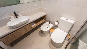 Une salle de bain moderne avec un lavabo blanc, un meuble-lavabo en bois, un bidet et des toilettes.