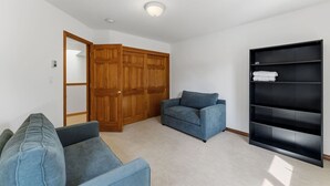 A room with a wardrobe, a sofa, a chair, and a built-in shelving unit. - EagleVail Mountain Retreat w/Large Deck & Fire Pit (Avon)