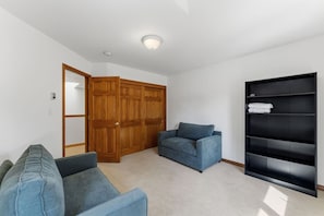 Una habitación con armario, sofá, silla y estantería empotrada.