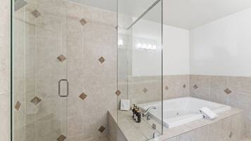 A modern bathroom with a glass shower enclosure, a large bathtub, and a mirror.