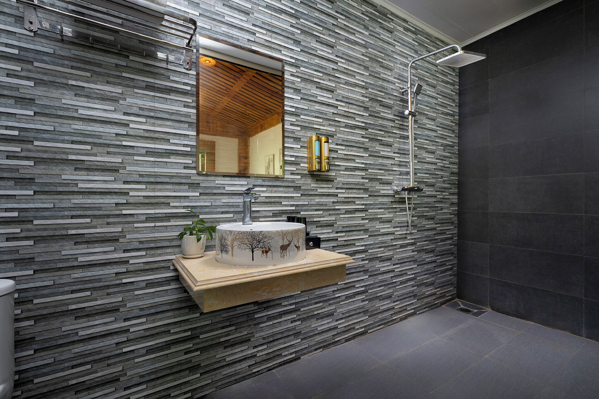 Un baño moderno con pared de textura pétrea, un lavabo con una pila decorativa, un espejo y una zona de ducha.