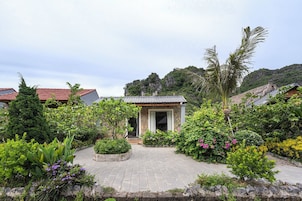 Un jardín con un edificio de piedra, rodeado de diversas plantas y árboles.