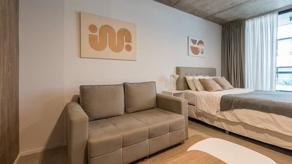 Een moderne hotelkamer met een bank, een bed en abstracte wanddecoratie.