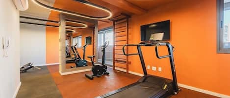 A gym with treadmills, exercise equipment, and a mirrored wall.