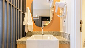 A bathroom with a white sink, a towel hanging on the wall, and a hairdryer mounted on the wall. - Arte Onze de Junho (São Paulo)