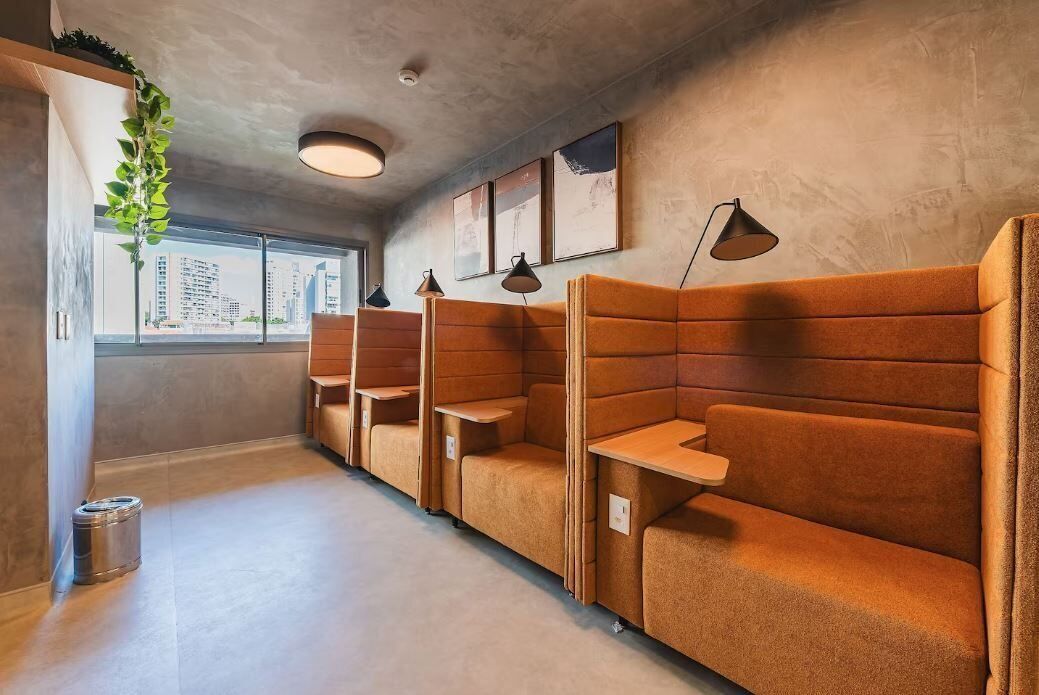 Un interior moderno con asientos acolchados, iluminación colgante y vistas a la ciudad a través de amplias ventanas.