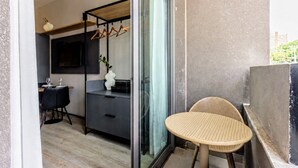 A modern interior with a dining area, a kitchenette, and a balcony with a wicker chair. - Arte Onze de Junho (São Paulo)