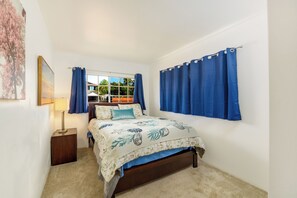 A bedroom with a bed, curtains, a window, and a nightstand.