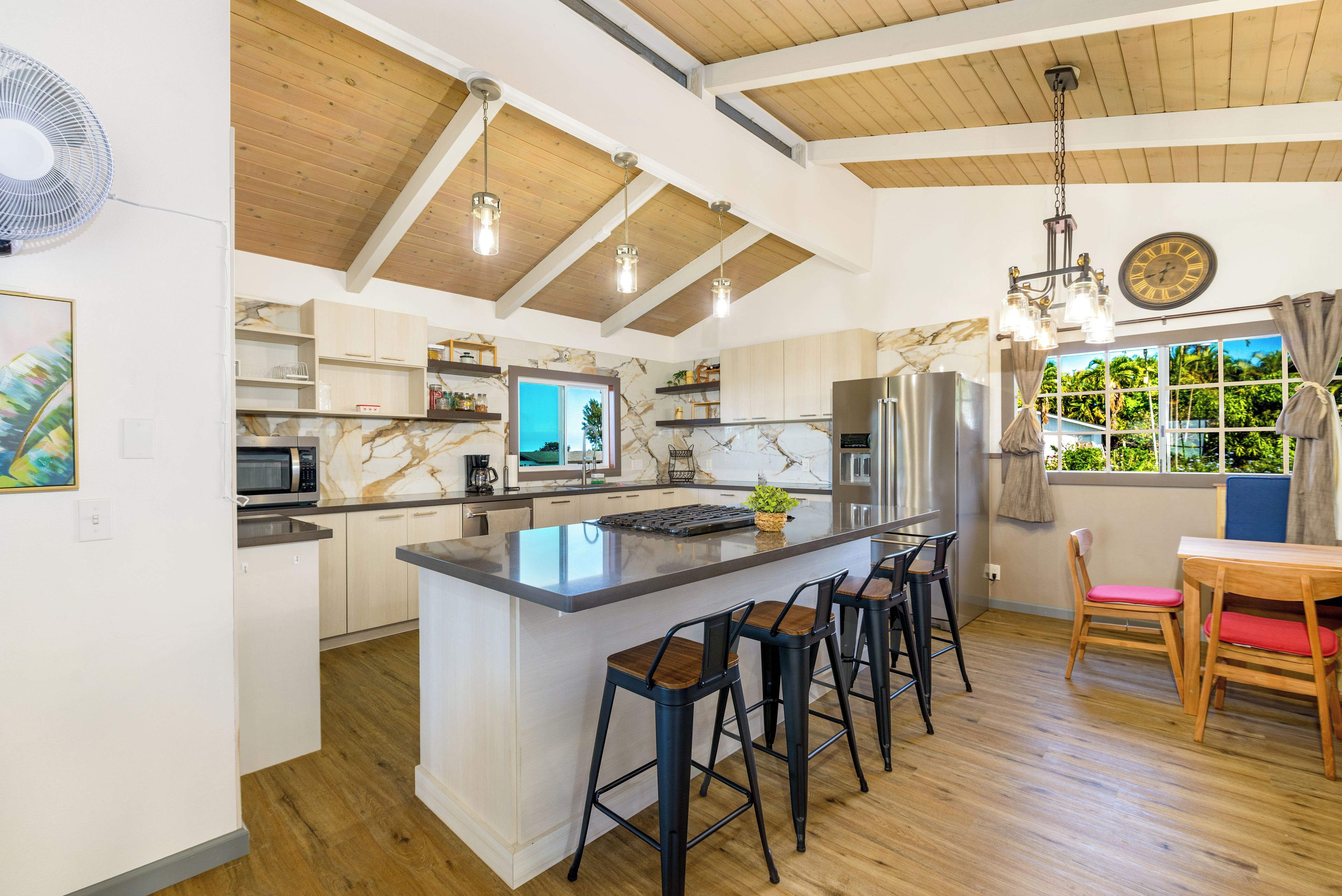 A modern kitchen with a central island, bar stools, and a dining area with a view.