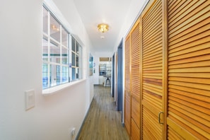 A hallway with a wooden door, a window with a view, and a ceiling light fixture.