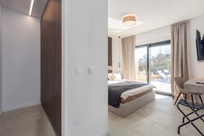 Un dormitorio moderno con cama, escritorio y vistas al exterior.