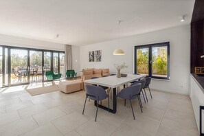 Ein modernes Wohnzimmer mit Essbereich, großen Fenstern und Blick ins Freie.