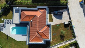 Eine Dachterrasse mit Pool, einer überdachten Terrasse und einem in der Nähe stehenden Auto.