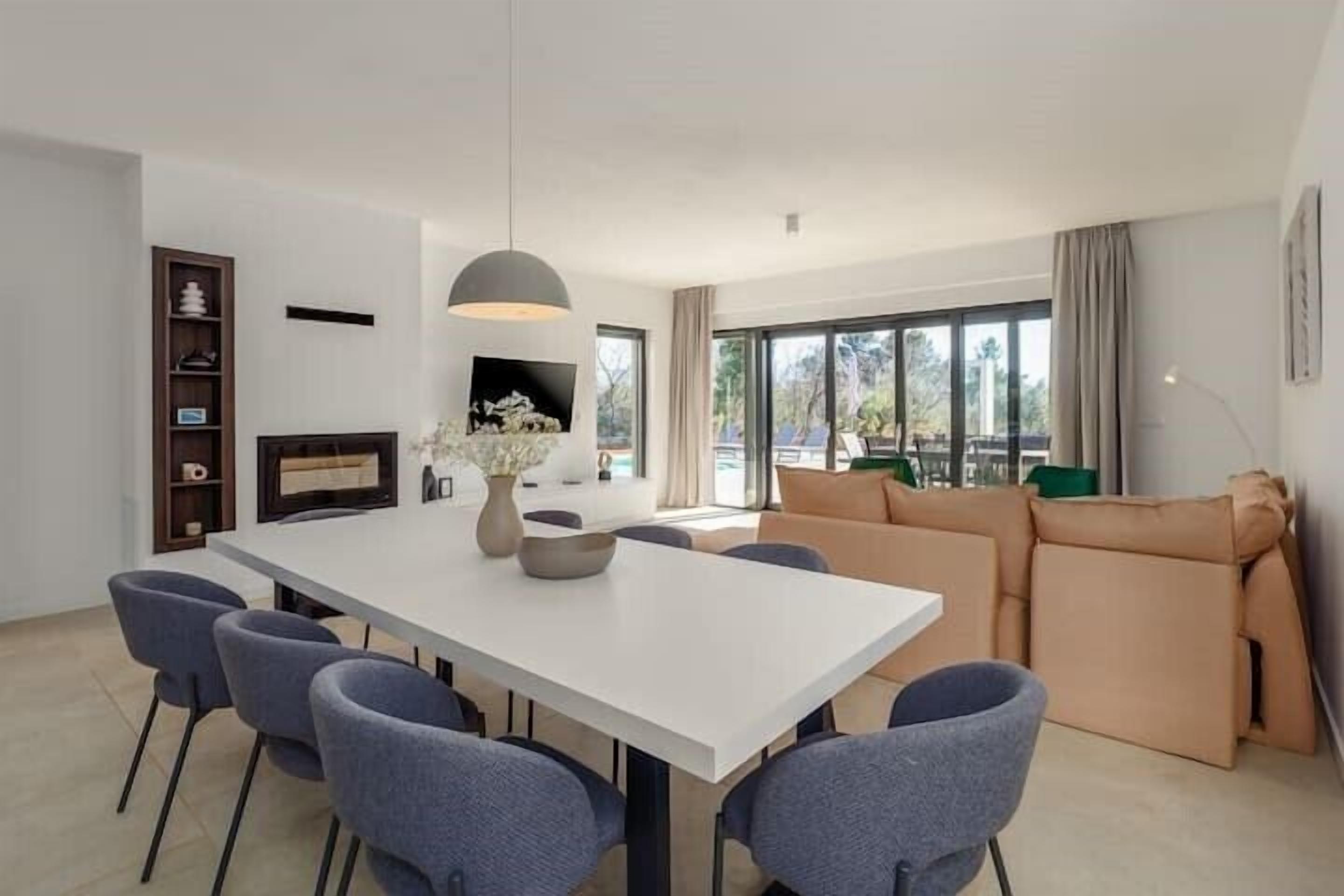 A modern living room with a dining table, sofas, and a fireplace.