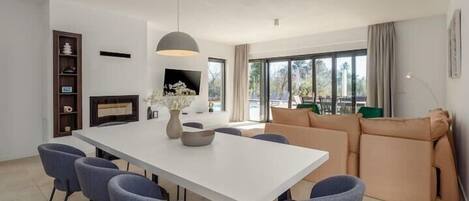 A modern living room with a dining table, sofas, and a fireplace.